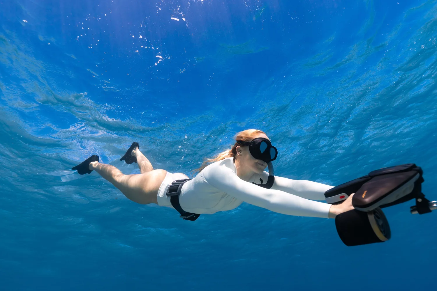Nageuse tractée par un scooter sous-marin Sublue, visage tourné vers l'objectif